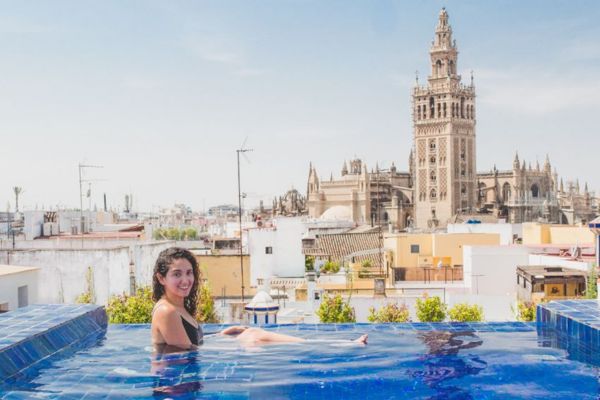 Woman relaxing in a rooftop pool with a panoramic view of Sevilla’s skyline in summer heat